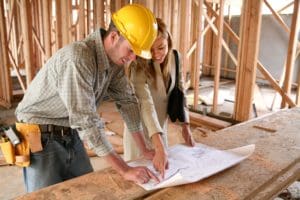 A man and woman in hard hats looking at plans.