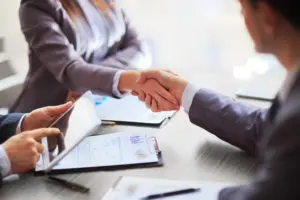 Two people shaking hands over a table.