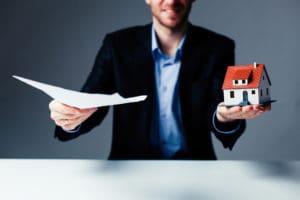 A man holding papers and a small house.