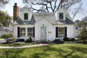 A white house with black shutters and a green lawn.