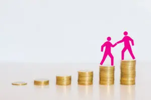 A pink paper cut out of two men on top of stacks of coins.