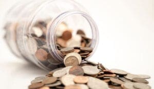 A jar of coins spilling out onto the ground.