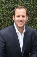 A man in a suit and tie smiling for the camera.