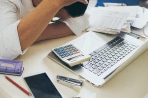 A person sitting at a desk with a calculator and laptop.