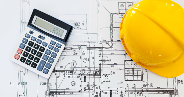 A calculator and hard hat sitting on top of a construction plan.