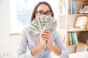 A woman holding money in front of her face.