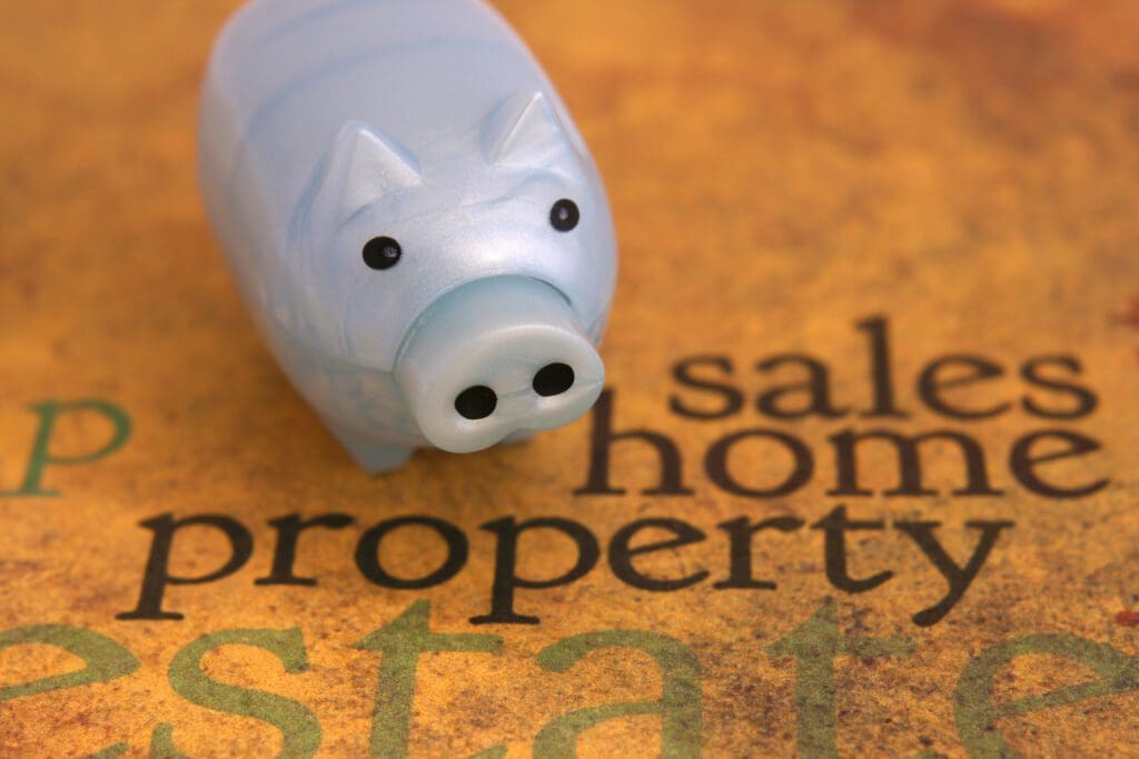 A toy pig sitting on top of the words " sale, home and property."