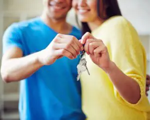 A man and woman holding keys to their new home.