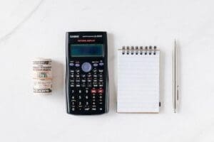 A calculator, notebook and pen on top of the table.