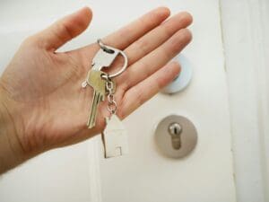 A hand holding keys with a key ring in the palm of his hand.