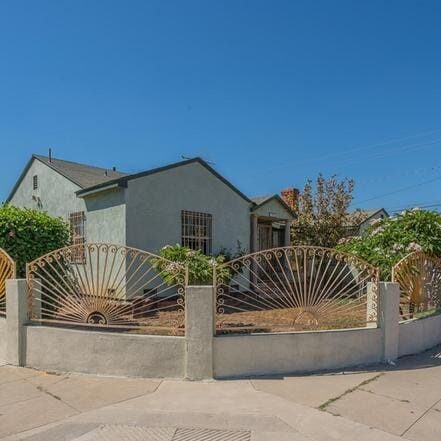 A house with a fence and palm trees in front of it.