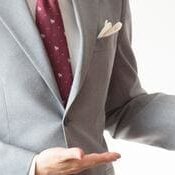 A man in a suit and tie holding his hand out.