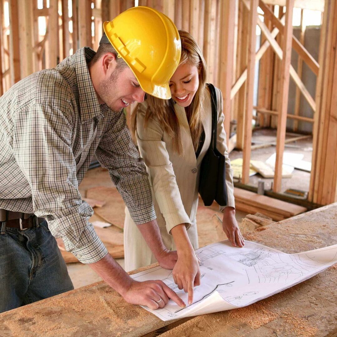 A man and woman in hard hats looking at plans.