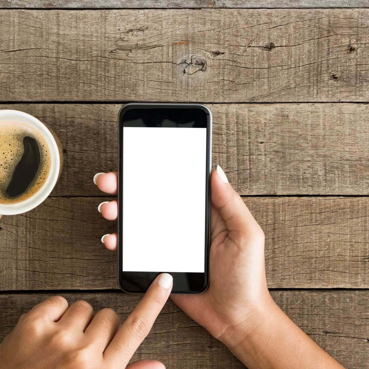 Hand tapping phone beside cup of coffee