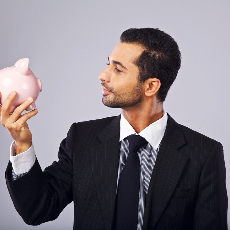 A man in a suit holding a piggy bank.
