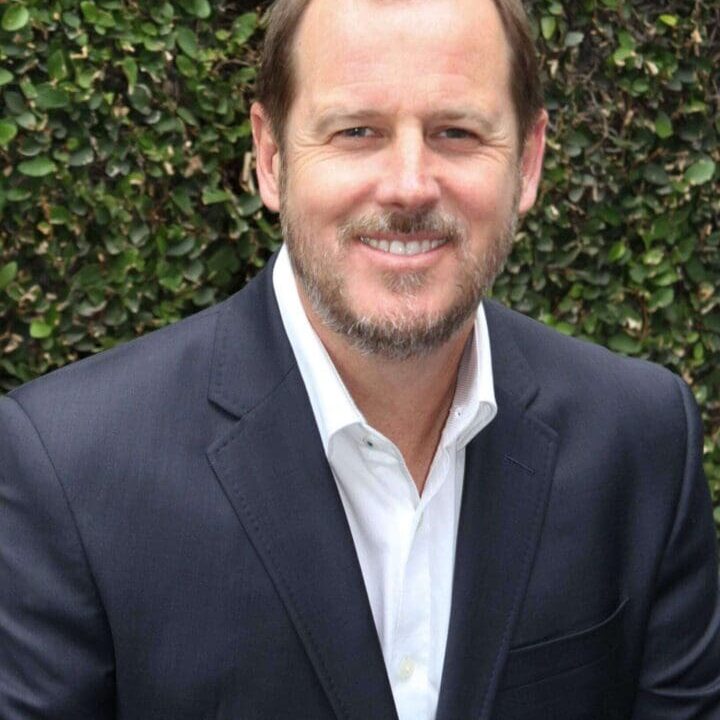 Casually posed businessman in suit near foliage