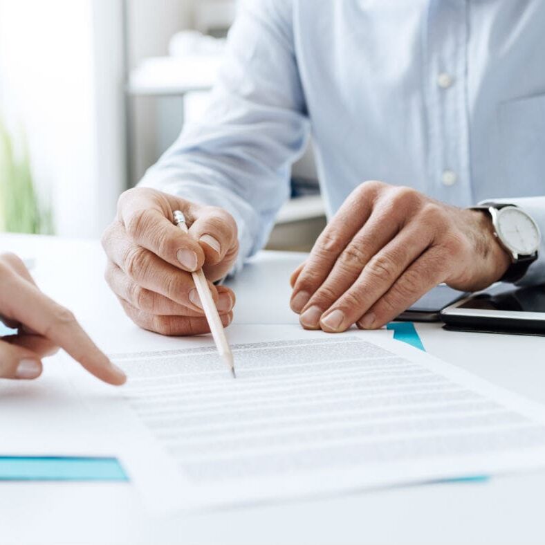 Two people are sitting at a table and one is holding a pencil
