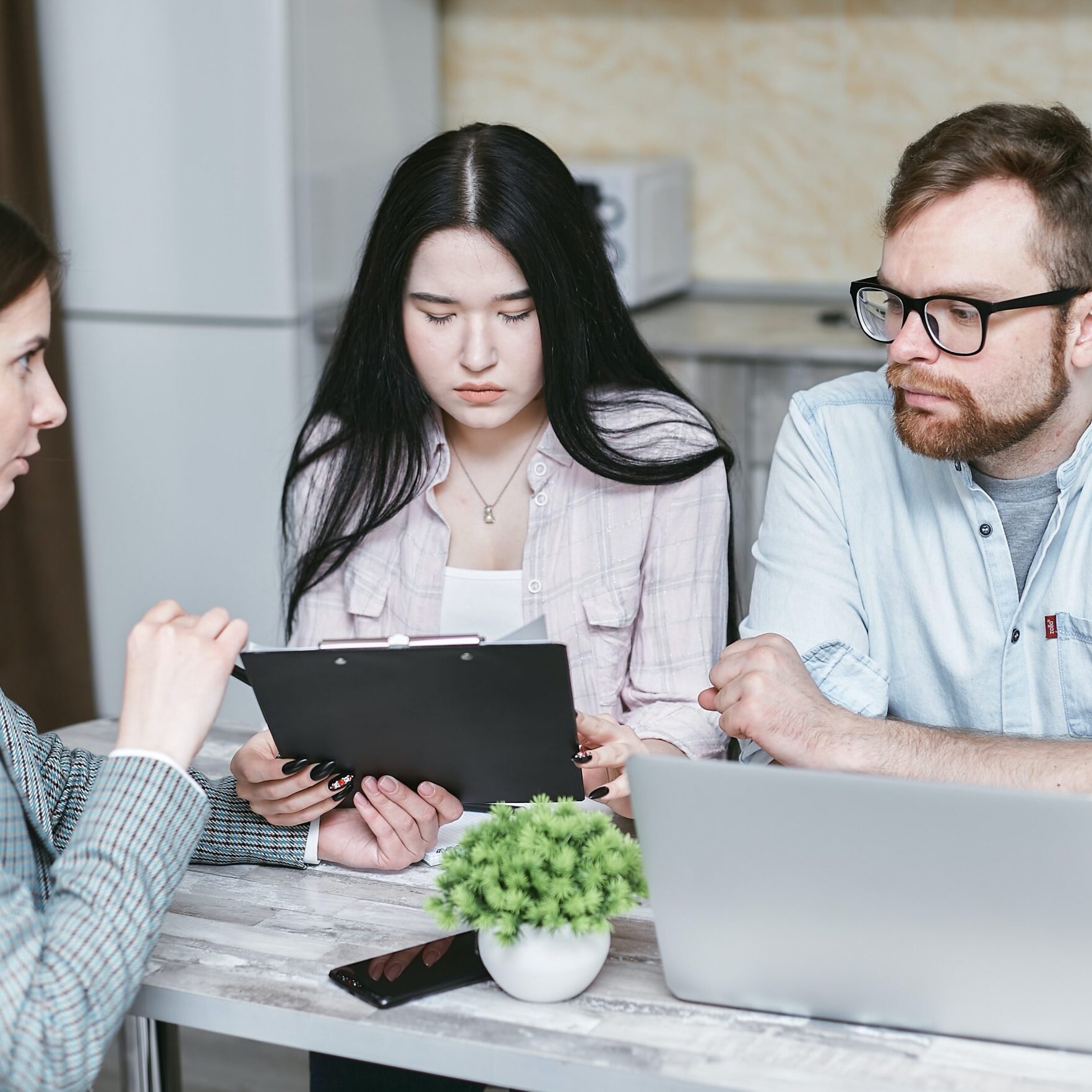 Three people sitting at a table with laptops