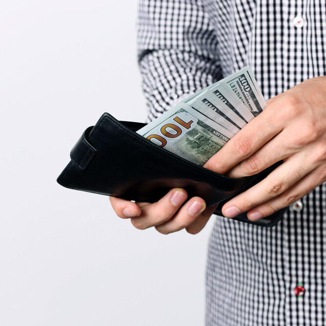 A man holding a wallet with money in it.