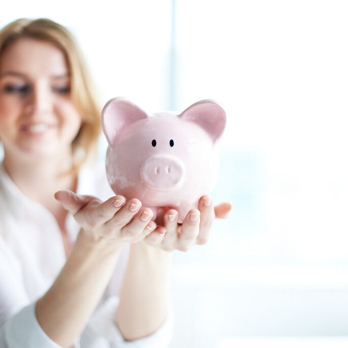 A woman holding out her hands and a piggy bank.