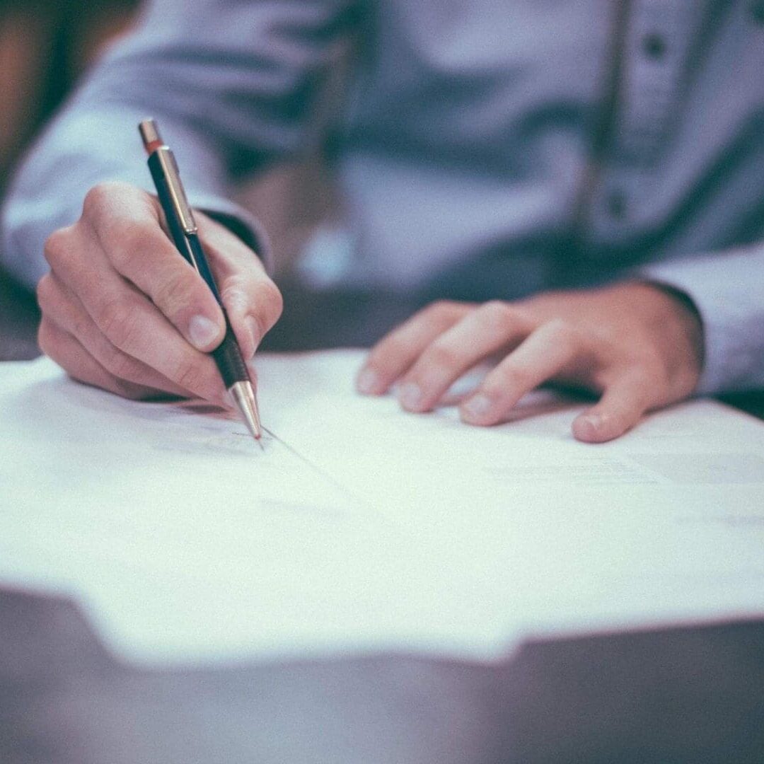 A person writing on paper with a pen.
